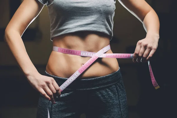 Delgado chica culturistas centímetro que mide su cintura en un gimnasio — Foto de Stock