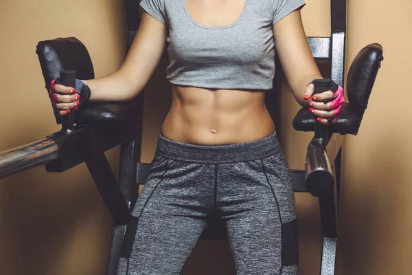 Mince, bodybuilder girl, balance la presse sur le ventre tout en s'entraînant dans la salle de gym — Photo