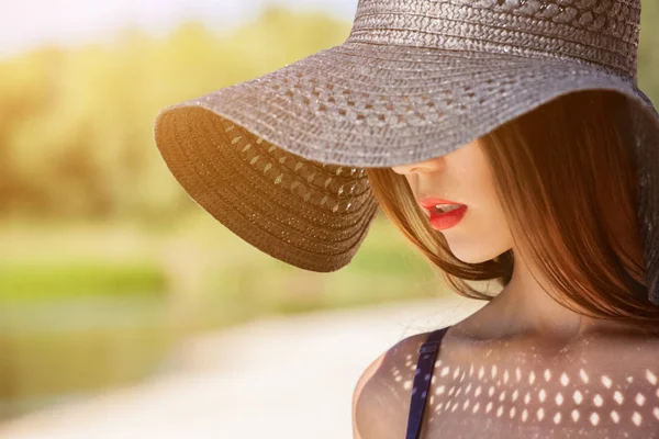 Muchacha atractiva en un sombrero negro usado en la cabeza, en la playa . — Foto de Stock