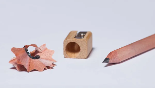 A wooden simple pencil, a pencil sharpener and shavings — Stock Photo, Image