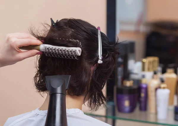 Парикмахер сушит волосы брюнетка — стоковое фото
