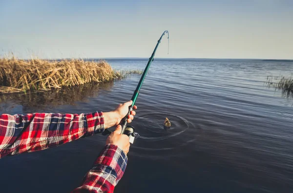 Rybáři úlovky ryb na břehu jezera, drží ruce spinning — Stock fotografie