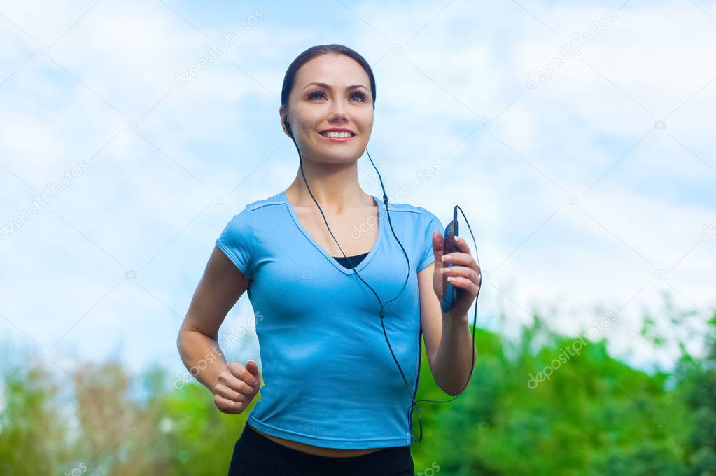 Young athlete running in the park and listens to music in summer, morning exercise