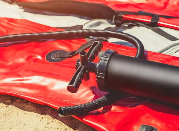 La bomba de plástico se encuentra en un barco soplado para hacer kayak en la playa . — Foto de Stock