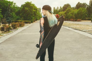 Dövme standları bir longboard ile mavi saçlı bir hippi güzel, seksi sarışın