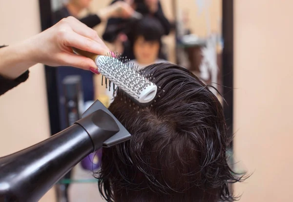 De kapper droogt haar haar een brunette meisje — Stockfoto