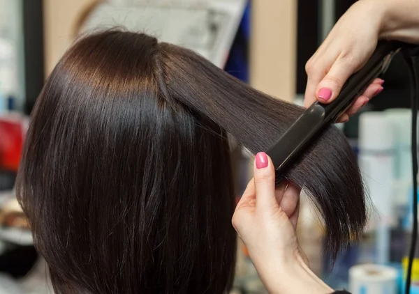 Fryzjerka wyrównuje włosów z włosów żelazko — Zdjęcie stockowe