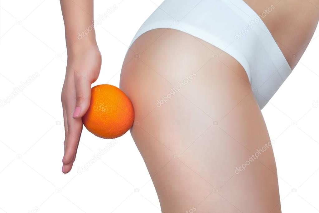 A thin girl is holding an orange by her ass
