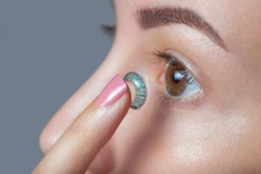 kadın mavi bir kontakt lens parmağına tutar. Göz bakımı ve vizyon geliştirmek için araç arasında seçim.