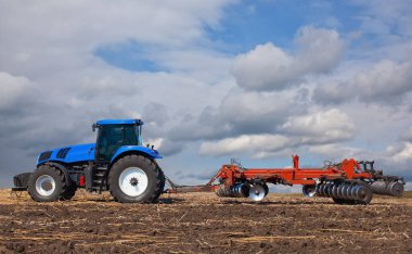 büyük mavi traktör, tarlayı güzel gökyüzüne karşı. Tarım makineleri eseri. Hasat