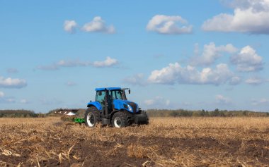 büyük mavi traktör, tarlayı güzel gökyüzüne karşı. Tarım makineleri eseri. Hasat