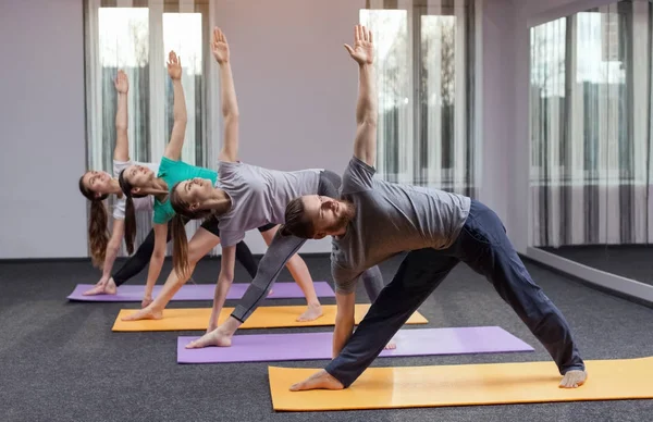 Three beautiful girls and man do yoga in the center of yoga and spa. The concept of a healthy lifestyle.