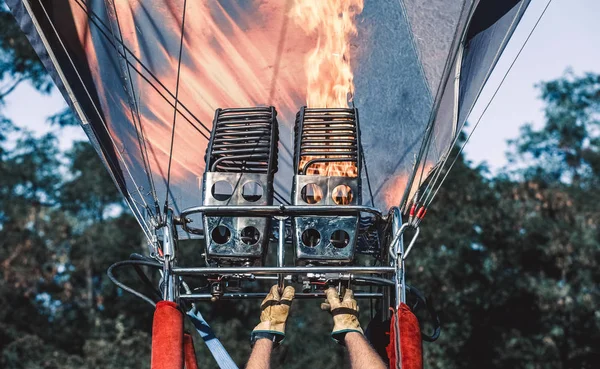 A man in gloves lights a balloon burner before flying.