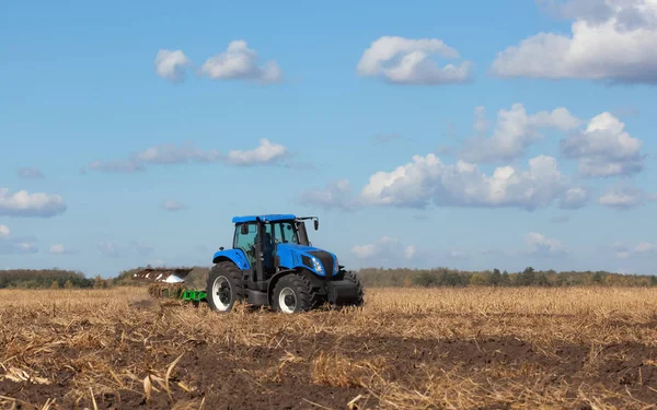 büyük mavi traktör, tarlayı güzel gökyüzüne karşı. Tarım makineleri eseri. Hasat