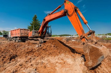 Kazıcı kargoyu yazın gökyüzüne karşı arabaya yüklüyor.