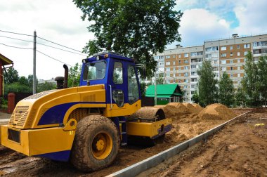 Traktör tekerleği, yazın yeni bir mahallede yeni bir yol inşa etmek için kumu hizalar.