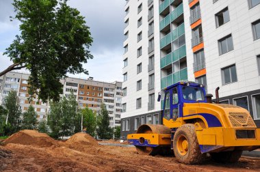 Traktör tekerleği, yazın yeni bir mahallede yeni bir yol inşa etmek için kumu hizalar.