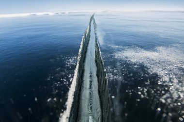 Kışın, güneşli bir havada, bir kış gölünün buzunda çatlar.