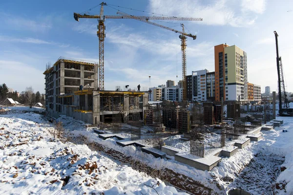 Kış aylarında inşaat halindeki yeni bir evin ön planındaki tıkanmış yığınlar bir vincin arka planına karşı.