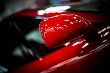 Kırmızı, modern bir yarış arabasının yan aynası. Arkaplanı bulanık.