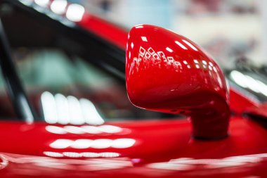 Kırmızı, modern bir yarış arabasının yan aynası. Arkaplanı bulanık.