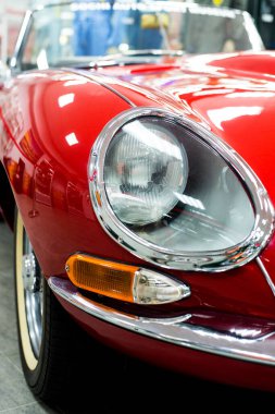 Kırmızı retro yarış arabasının ışıklarıyla krom far. Arka planda bulanıklık var.
