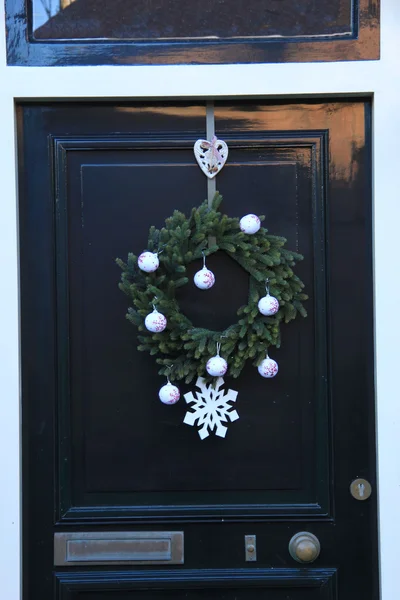 Clásica corona de Navidad con decoraciones en una puerta —  Fotos de Stock