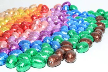 Bir grup folyo sarılıp gökkuşağı renklerine bürünmüş çikolatalı yumurta.