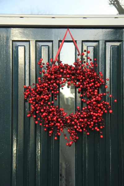 Grinalda de Natal de baga com decorações em uma porta — Fotografia de Stock