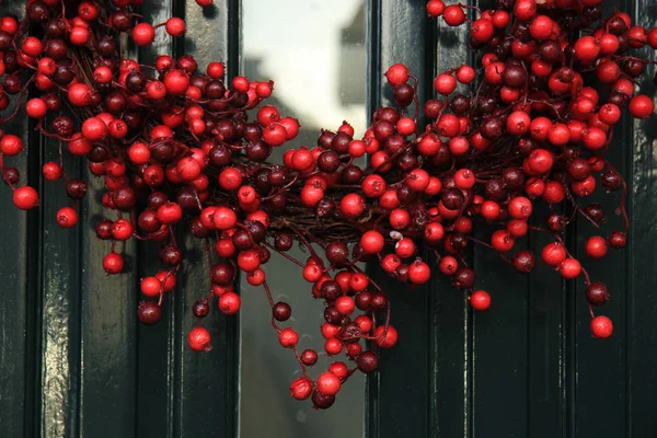 Berry christmas wreath with decorations on a door — Stock Photo, Image