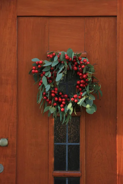 Grinalda de Natal de baga com decorações em uma porta — Fotografia de Stock