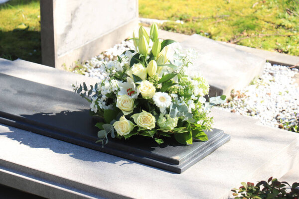 White funeral flowers on a grey marble tomb