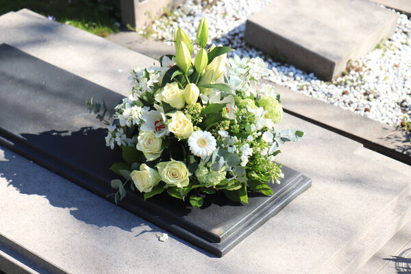 White funeral flowers on a grey marble tomb