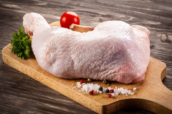 Perna de frango crua na placa de corte — Fotografia de Stock