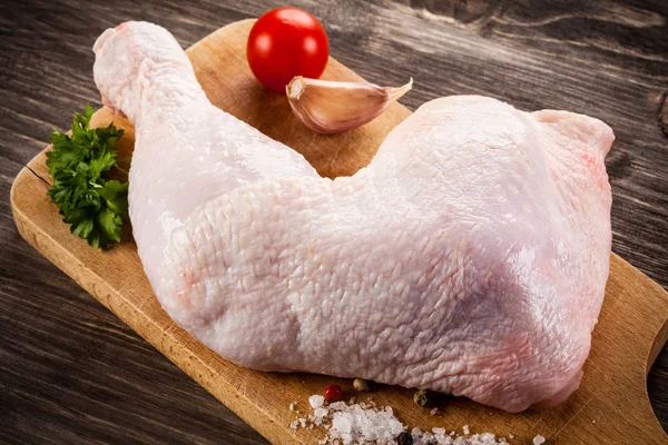 Pierna de pollo crudo en la tabla de cortar —  Fotos de Stock