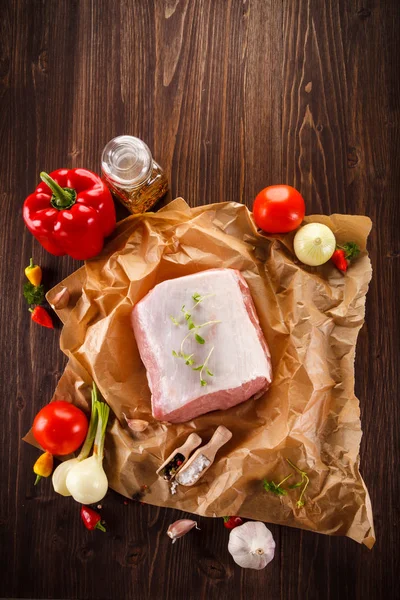 Свежая сырая свинина с овощами на деревянной баколе — стоковое фото
