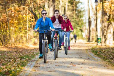Healthy lifestyle - people riding bicycles in city park clipart