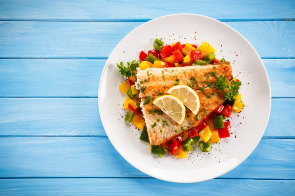 Fish dish - fried fish fillet and vegetables on wooden table