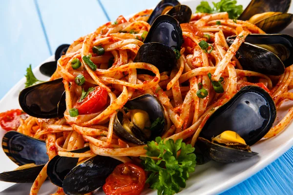 Cooked mussels and pasta on wooden table