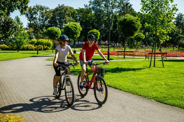 男子和妇女在夏季公园骑自行车 — 图库照片