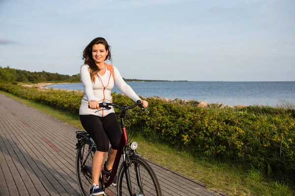 海辺で自転車に乗る若い女性 — ストック写真