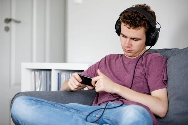 Hombre Joven Usando Smartphone Auriculares Sentados Sofá —  Fotos de Stock