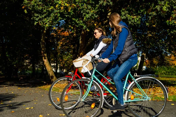 秋の公園で一緒に自転車に乗る母と娘 — ストック写真