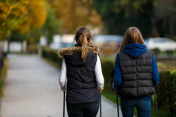 Madre Hija Caminando Juntas Parque Otoñal Usando Palos Turistas Caminata —  Fotos de Stock