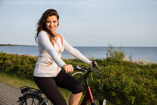 海辺で自転車に乗る若い女性 — ストック写真