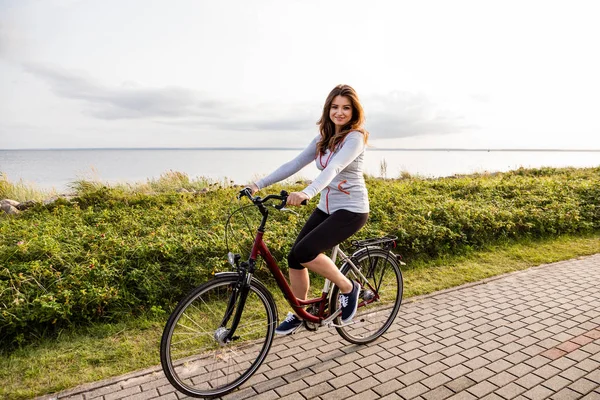 海辺で自転車に乗る若い女性 — ストック写真