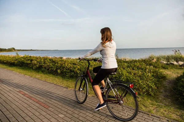 年轻女子在海滨骑自行车 — 图库照片