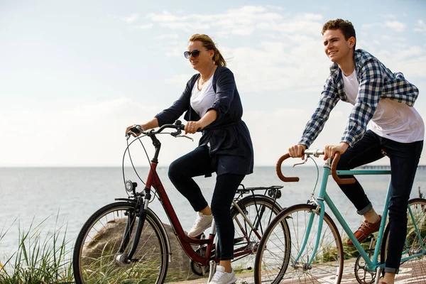 川の近くに自転車に乗るカジュアルな服装の女性と男性 — ストック写真