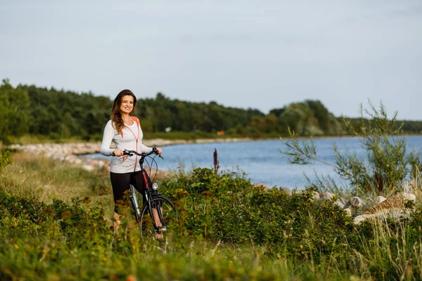 年轻女子在海滨骑自行车 — 图库照片