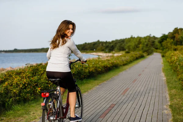 海辺で自転車に乗る若い女性 — ストック写真